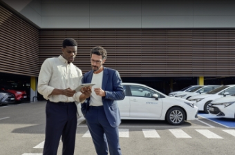 Dwóch mężczyzn stoi na placu salonu dealerskiego wśród zaparkowanych samochodów