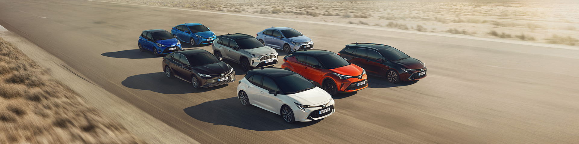 Dynamiczne ujęcie siedmiu modeli Toyoty jadących drogą.